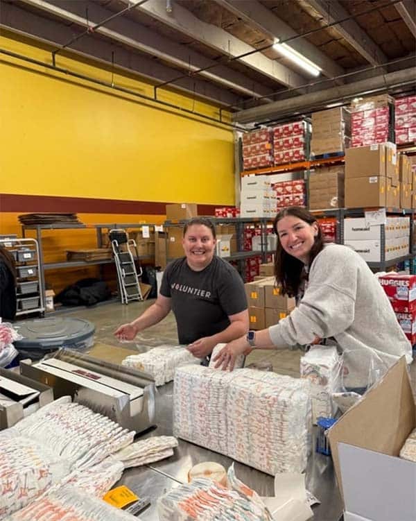 Two women packing diapers in a warehouse